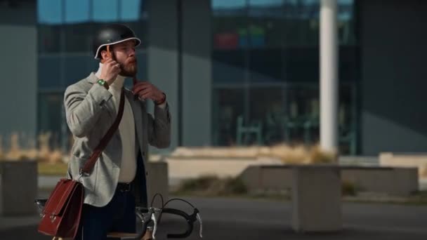 Genç işadamı bisiklet sürmeden önce kask takıyor. İşe gitmek için seyahat ediyor. Güvenlik ve çevre dostu ulaşım — Stok video