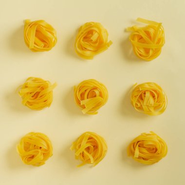 Düz görünüm fettucine makarna sarı pastel arkaplan kopyalama alanı üzerinde yatıyordu