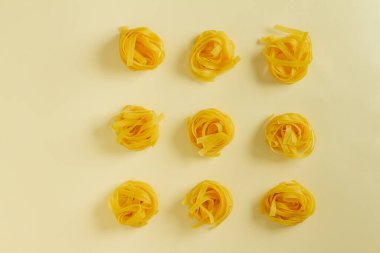 Düz görünüm fettucine makarna sarı pastel arkaplan kopyalama alanı üzerinde yatıyordu