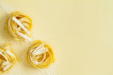 Düz görünüm fettucine makarna sarı pastel arkaplan kopyalama alanı üzerinde yatıyordu