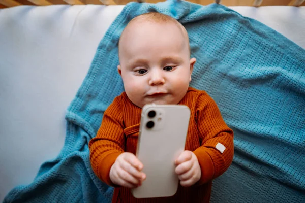 Bébé tout-petit tenant smartphone. Regarder une vidéo sur smartphone. — Photo