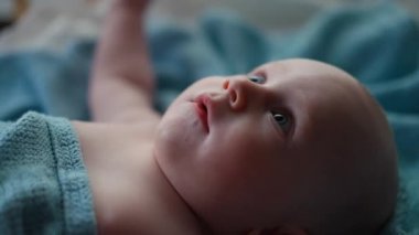 Yan görünüm orta bölüm. Küçük çocuk mavi gözlü, çocuk gülüyor ve yatakta mutlu.