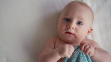 Sevimli bebek gülümsüyor ve yatakta uzanıyor. Kopyalama alanı olan. Kameraya bakıyorum..