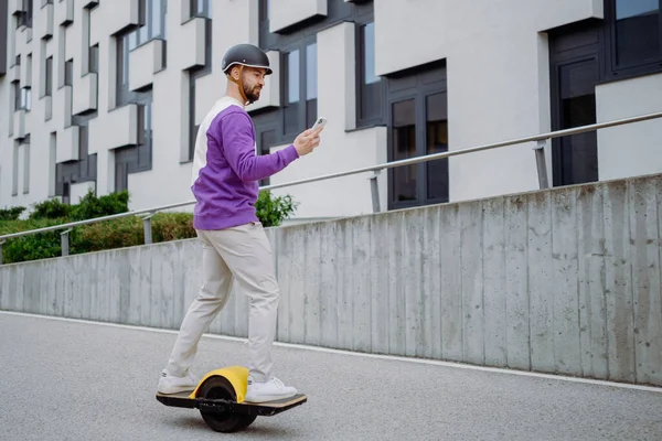 European man with electric skateboard. Young handsome man using the phone. — Stock Photo, Image