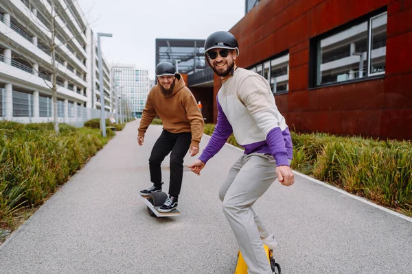 Δύο άνδρες οδηγούν στο μέλλον Segway. Ηλεκτρικό συνεργείο σκέιτμπορντ. το μελλοντικό ζωντανό στυλ. Αστικό υπόβαθρο — Φωτογραφία Αρχείου