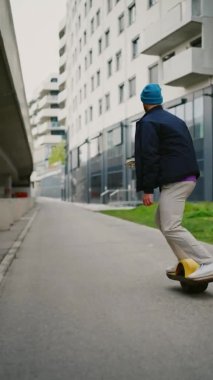 Genç adam tek tekerli bisiklete binmekten hoşlanıyor. Elektrikli kaykay. Dikey görüntü 4K