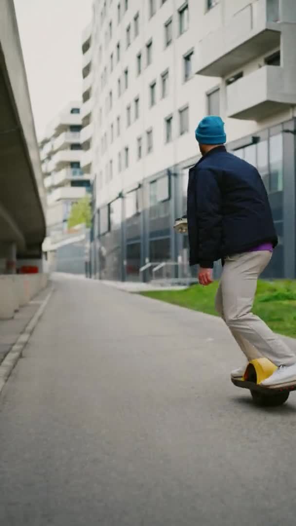 Mladý muž si užívá jízdu na jednokolce. Elektrický skateboard. Svislý záznam 4K — Stock video