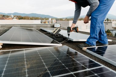 Adam işçi tornavida kullanarak güneş fotovoltaik panel sistemi kuruyor. Alternatif enerji kavramı