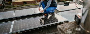 İşçi aile evinin çatısına yeni güneş panelleri kuruyor. Alternatif enerji. Kapak fotoğrafı