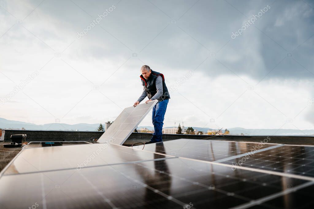 Man installing solar photovoltaic panel system. Technician working with solar panels. Eco concept alternative energy