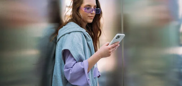 Portrett av en ung, kul kvinne med smarttelefon. Sender tekstmeldinger. Isolert på bakgrunn – stockfoto