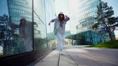 Hip hop kapüşonlu, Whit City arka planında dans eden aktif şehir kızı. Havalı yetenekli kız dansçı serbest stil hip-hop müzik ritmine göre hareket eder.