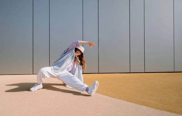 Nuori hip hop tyttö ylisuuri asu yllään tanssia musiikin minimalistinen kaupunkien tausta. Hip-hop-kuningatar. Aamiaisnainen. minimalistinen — kuvapankkivalokuva