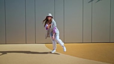 Young hip hop girl in oversize outfit wearing dancing into music minimalistic urban background. Hip-hop queen. Breakdancer woman. minimalistic 