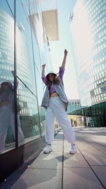 Hip hop kapüşonlu, Whit City arka planında dans eden aktif şehir kızı. Havalı yetenekli kız dansçı serbest stil hip-hop müzik ritmine göre hareket eder.