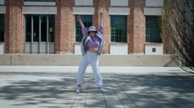 Beautiful and happy European girl having fun dancing break dance hip hop freestyle outdoors.