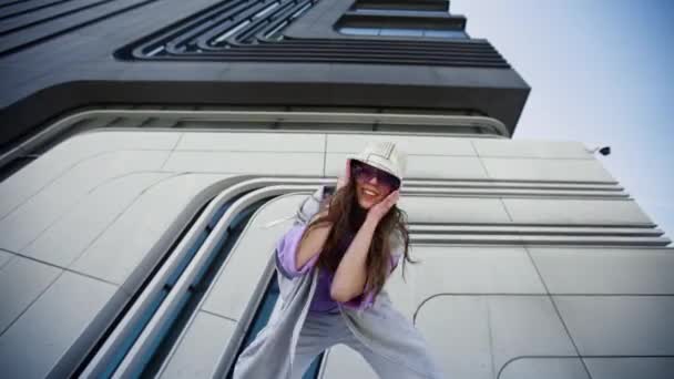Fröhliches kaukasisches Mädchen im Hip-Hop-Outfit, das zu Musik unter der Straße tanzt. Urbaner Hintergrund. Weitschuss — Stockvideo