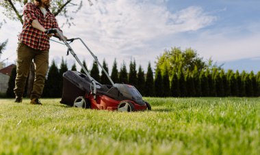 Adam evdeki çimleri biçiyor. Bahçe aletleri kavramı