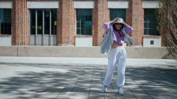 Fashion cute woman with hat dancing outside whit copy space. Female dancer points to the side of the text. — Video