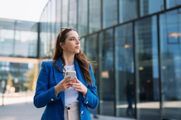 Modern businesswoman in blue suit using mobile phone. Looking away. Copyspace — ストック写真