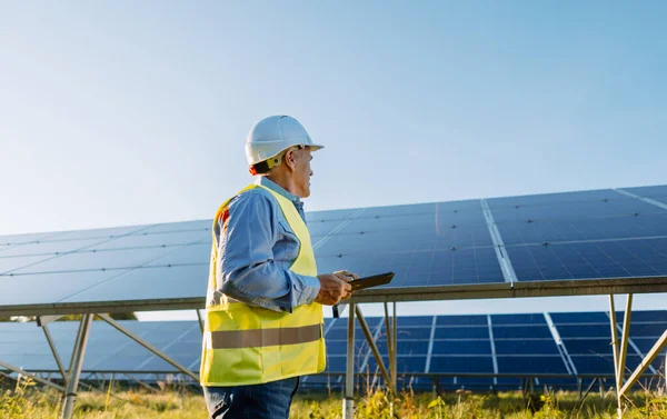 İşçi güneş panellerini güneş çiftliğindeki tabletle kontrol ediyor. Çevre enerjisi. Yüksek kalite fotoğraf