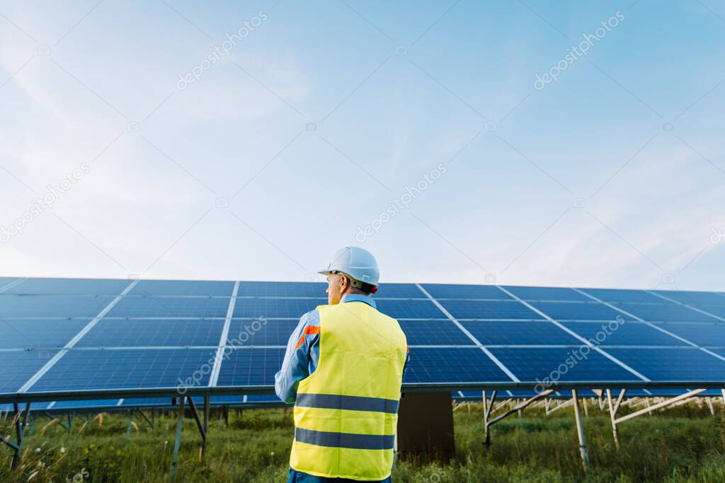 Rear view of worker at solar farm. Solar photovoltaic panels. Eco Alternative energy concept. High quality photo