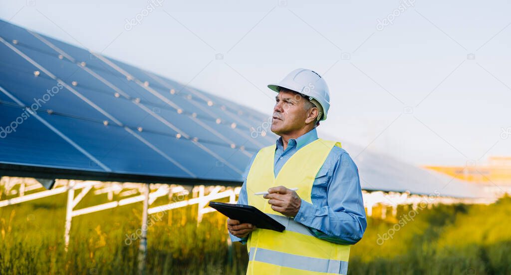 Portrait of engineer working with digital tablet at solar farm. Alternative Eco energy concept. High quality photo