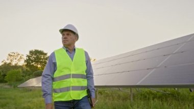 Güneş enerjisi tarlasında yürüyen kıdemli işçiler ve güneş dizisi yazılım sistemini izleyen. Güneş panelleri temiz enerji üretiyor. Yenilenebilir kaynaklar kavramı 