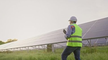 Mature solar energy specialist walking at a solar power facility. Professional engineer thinking about innovative project