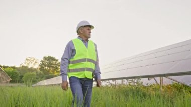 Güneş santrali çiftliğinde tabletleri olan kıdemli mühendis. Trafo platformunda yürürken elinde tabletle gezen yetişkin adamlar. Temiz enerji konseptinin taşınması