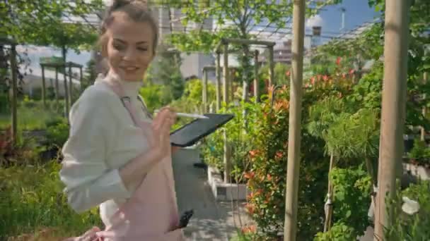 Young Woman Gardener Apron Dancing Greenhouse Woman Holding Tablet Having — Αρχείο Βίντεο