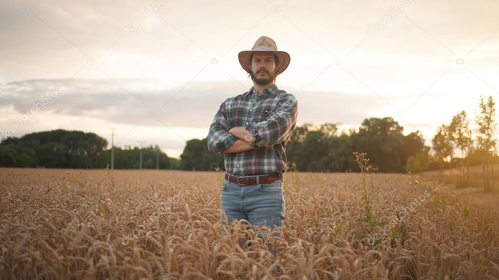 Portrait of the cheerful and happy young man farmer in hat and plaid shirt smiling positively and looking at the camera 