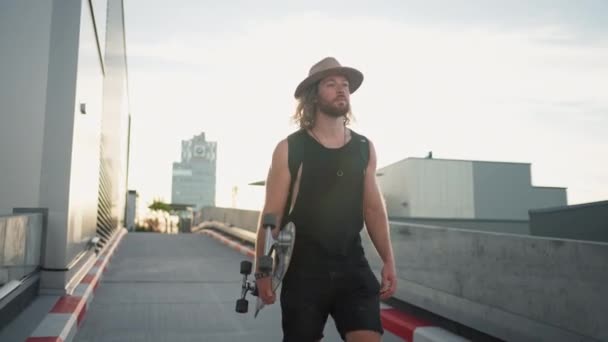 Trendy Cool Man Holding Skate Board Looking Away While Walking — Video