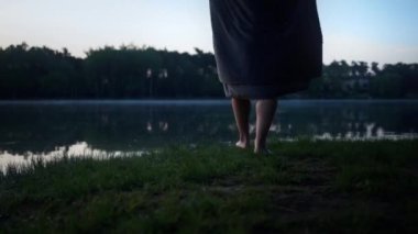 Closeup view of the man wearing swimsuit throwing towel from his shoulders at the ground entering at the cold winter lake at morning. Guy preparing for the ice swimming