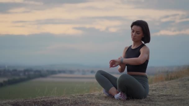 Young Beautiful Woman Looking Smartwatch While Sitting Lotus Yoga Position — Video