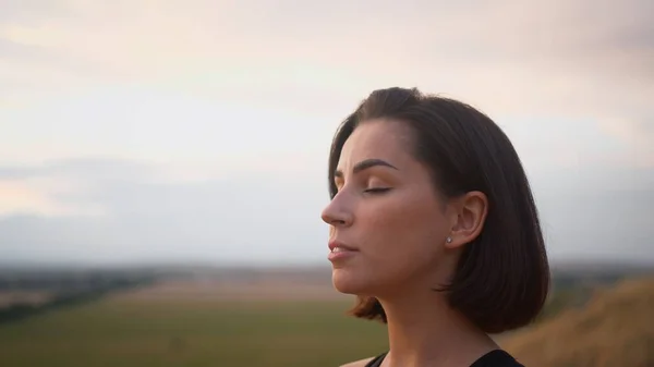 Calm woman enjoying free time for yoga practice and making breath exercises. Attractive female with closed eyes feeling good during zen research and asanas