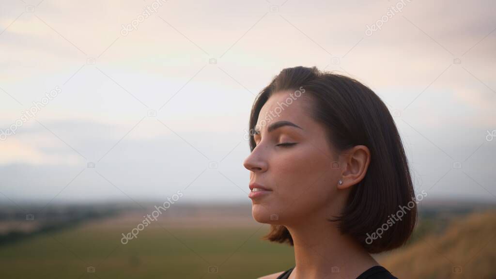 Calm woman enjoying free time for yoga practice and making breath exercises. Attractive female with closed eyes feeling good during zen research and asanas