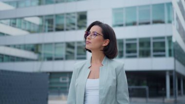 Successful businesswoman standing near office modern business center. Happy woman smiling while using smartphone, writing text message, check social media and work emails