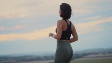 Yazın akşamları kırsal alanda koşan genç bir kız. Kadın koşudan sonra akıllı saat uygulamasında sonuçları kontrol ediyor. Yaşam tarzı spor arka plan kavramı