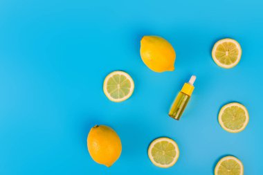 Mavi arka planda sarı dilimlenmiş limonlu pipetle şeffaf bir şişede serum. Cam bir kapta retinol ile kozmetik nemlendirici. Doğal güzellik organik nemlendirici yağ. Boşluğu kopyala