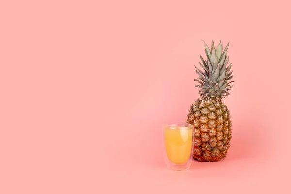 Ananas ve bir bardak ananas suyu izole edilmiş pastel pembe arka planda ve kopyalanmış. Minimum meyve konsepti. Beslenme kavramı