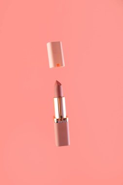 Pembe arka planda pembe ve altın rengi bir üst görüşe sahip çıplak matte ruj ve kapak. Makyaj sanatçısının işi için profesyonel kozmetik ürünü. Parlak arkaplan dikey.