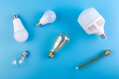 Lider lamba ve Edison kaotik bir şekilde izole edilmiş mavi bir arka planda yatıyor. Enerji verimliliği kavramı. Düz yatıyordu. Ekolojiyi kavra, dünyayı kurtar, fikri, enerjiyi, ekonomiyi, tasarrufu. Dünya günü