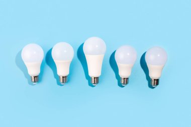 Öncü lambalar izole edilmiş mavi bir arka planda düz yatarlar. Enerji verimliliği kavramı. Düz yatıyordu. Ekolojiyi kavra, dünyayı kurtar, fikri, enerjiyi, ekonomiyi, tasarrufu. Dünya günü.