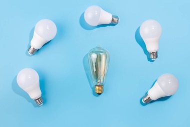 Edison lambası ortada, buz lambaları izole edilmiş mavi arka planda duruyor. Düz yatıyordu. Ekolojiyi kavra, dünyayı kurtar, fikri, enerjiyi, ekonomiyi, tasarrufu. Dünya günü. Akıllı alışveriş, satış.