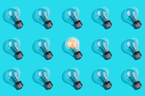 крупным планом лампы накаливания и одной светящейся лампы на изолированном синем фоне. Концепция энергоэффективности. Плоский лежал. Концепция экологии, спасения планеты Земля, идея, энергосбережение, экономика.