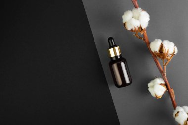 Pamuk kaplı ince dallı, gri, siyah geometrik arka planda gerekli yağlı pipetli cam kahverengi şişe. Deri ve saç bakımı için Aromatik Kozmetik Ürün.