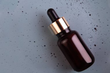 Gri arka plan manzaralı, kahverengi pipetli cam bir şişe. Cilt ve saç bakımı için Aromatik Kozmetik Ürün. Güzellik ürünlerini organik ile nemlendirir. Düz Yatay.