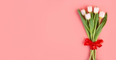 Flatlay güzel bir buket beyaz lale, kırmızı kurdeleyle bağlanmış, kopyalanmış pastel pembe arka planda. Kadınlar Günü için dekorasyon, Anneler Günü, yıldönümü. Bahar konsepti