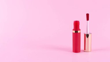 Applicator with liquid perfect red lipstick tube on pastel pink background. Space for text. Mockup and make up concept. 
